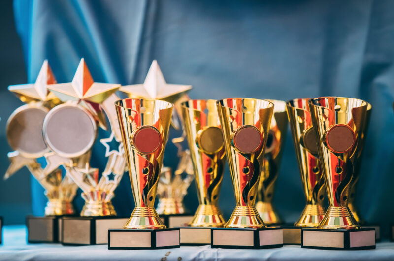 Different Champion Golden Trophy, Trophies. Winners Cups On Blue Cloth Background