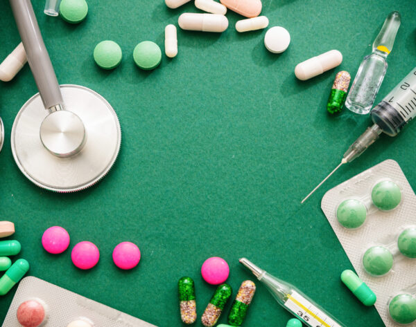 Medical supplies flat lay. Drugs medicine and syringes, stethoscope and thermometer, green background, top view
